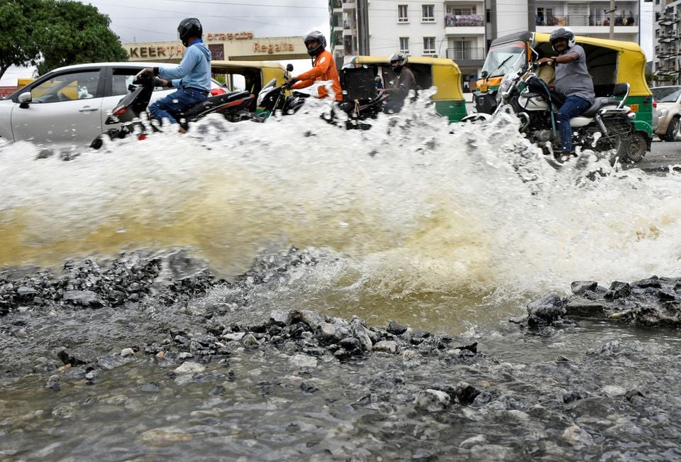 Traffic moves as water is pumped out of an inundated residential area following torrential rains in Bengaluru, India, September 7, 2022.