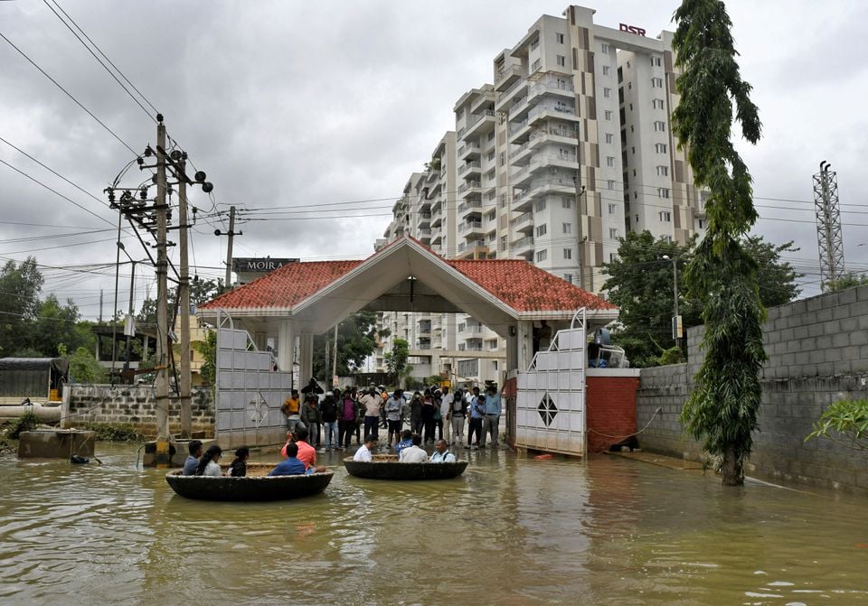 لوگ 7 ستمبر 2022 کو بنگلورو، انڈیا میں طوفانی بارشوں کے بعد پانی بھرے پڑوس سے گزرنے کے لیے کوریکل کشتیوں کا استعمال کر رہے ہیں۔