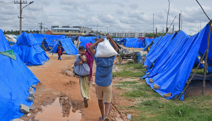 People living in a slum carry ration to their temporary shelters after rainwater flooded their dwelling in Bangalore on September 7, 2022. —AFP/Manjunath Kiran