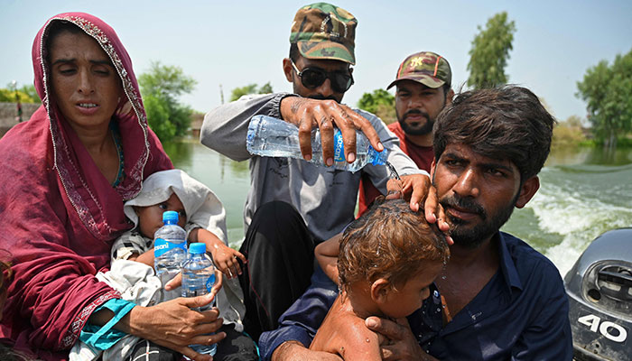 7 ستمبر 2022 کو صوبہ سندھ کے ضلع دادو میں مون سون کی شدید بارشوں کے بعد ایک چھوٹے سے پاکستانی گاؤں بستی احمد دین میں بحریہ کے اہلکاروں کی طرف سے سیلاب زدہ گھروں سے پھنسے ہوئے سیلاب سے متاثرہ رہائشی ایک کشتی میں بیٹھے ہیں۔ — AFP