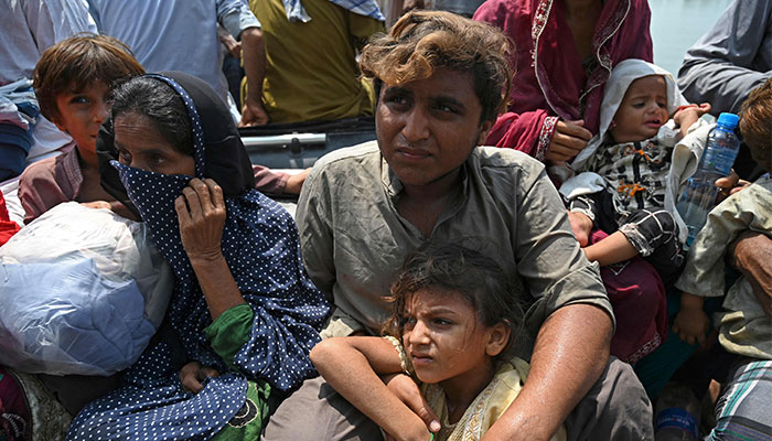 Stranded flood-affected residents sit in a boat after they were rescued from their flooded houses by Pakistan´s Naval personnel at Basti Ahmad Din on September 7, 2022. — AFP