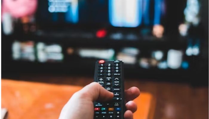 TV remote control in persons hand. Unsplash