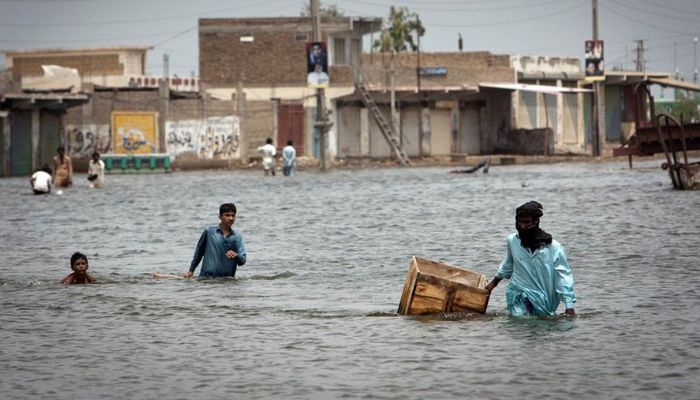 Men wade through flooded roads in Sindh — Reuters