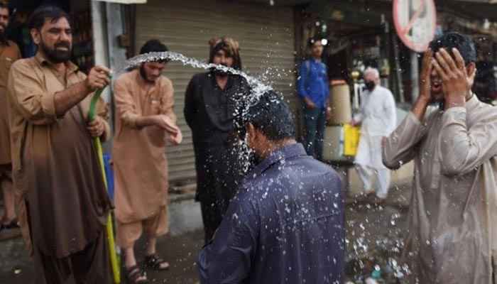 People spray each other with water as temperatures rise in Karachi. — AFP/File