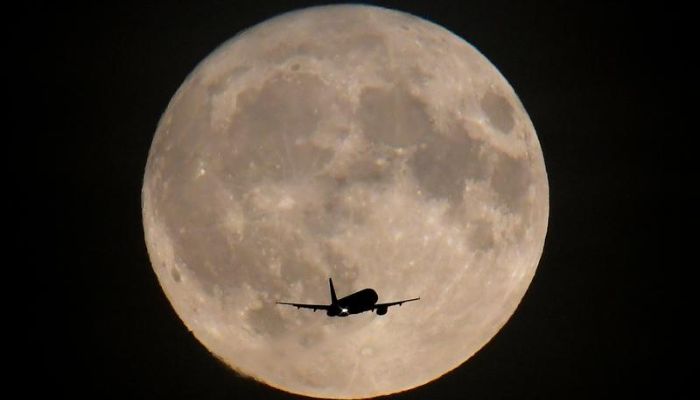 Passenger plane in front of the moon. — Reuters