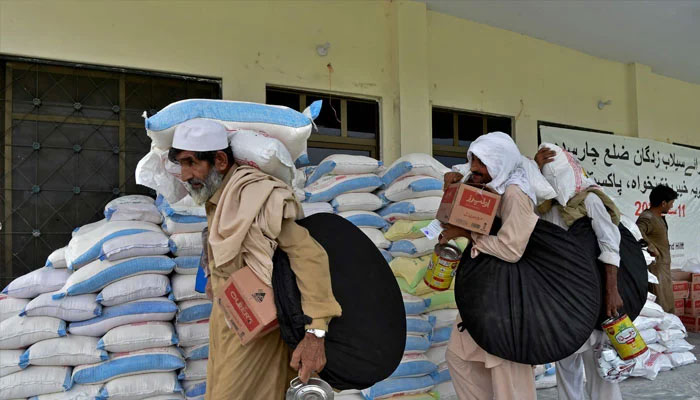 Flood-affected people receive relief supplies from a distribution center after heavy monsoon rains in Charsadda district of Khyber Pakhtunkhwa province on September 11, 2022. — AFP