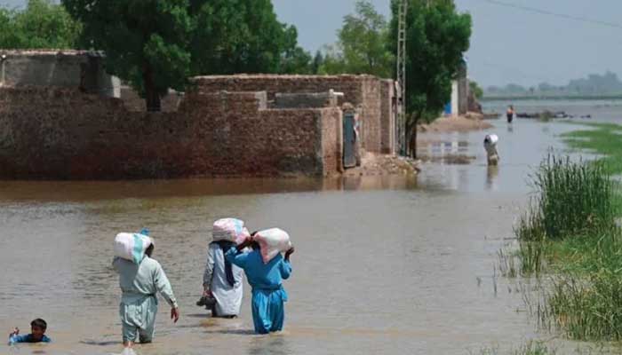 People wade through a flooded area in Jacobabad. Photo: AFP/file
