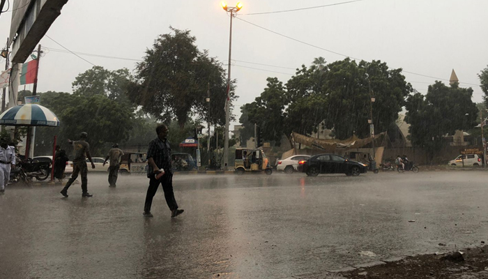 A person walks near II Chundrigar Road as it rains in Karachi, on September 12, 2022, after a few days of sweltering heat. — Ashir Ahmed
