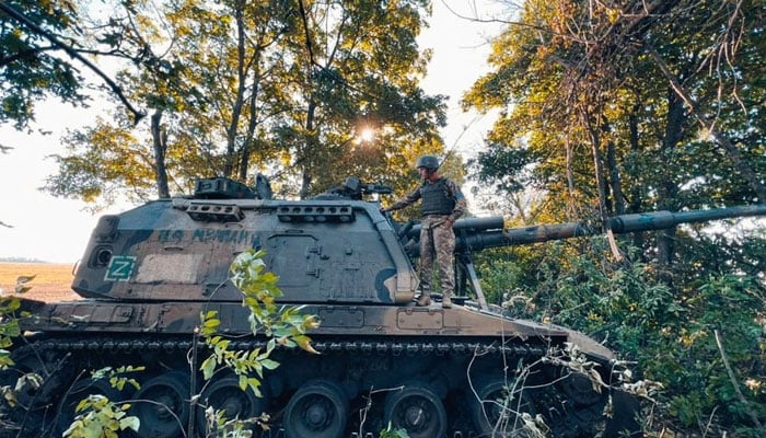 Seorang anggota layanan Ukraina berdiri di atas howitzer self-propelled 2S19 Msta-S Rusia yang ditangkap selama operasi serangan balasan, di tengah serangan Rusia ke Ukraina, di wilayah Kharkiv, Ukraina, dalam gambar selebaran yang dirilis 12 September 2022. — Reuters