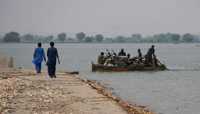 Residents use a boat to transport their motorcycles amid floodwater, following rains and floods during the monsoon season, in Manjhand town, in Jamshoro, Pakistan, September 12, 2022. — Reuters