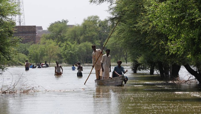 Warga menggunakan perahu sementara yang lain mengarungi banjir yang naik, menyusul hujan dan banjir selama musim hujan di pinggiran Bhan Syedabad, Pakistan 8 September 2022. — Reuters