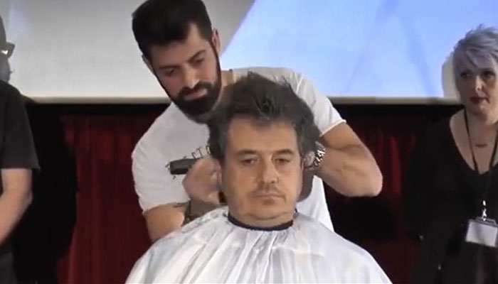 Konstantinos Koutoupis gives a man a haircut. — Screengrab Twitter video
