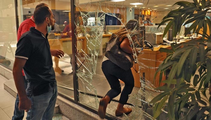 The glass facade of a bank in the Lebanese capital Beirut is broken, after a woman stormed it demanding access to her sister´s deposits to allegedly pay for her hospital fees, on September 14, 2022. — AFP