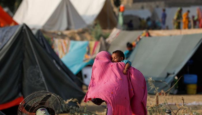 A woman who became displaced walks with her baby amid tents, following rains and floods during the monsoon season in Sehwan, Pakistan September 13, 2022. — Reuters