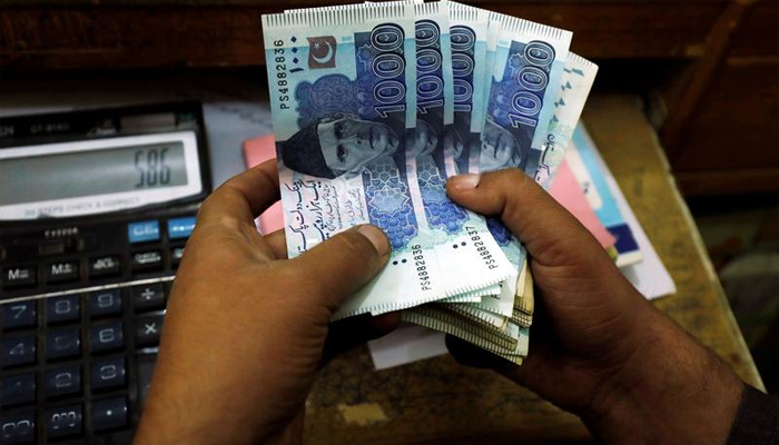 A trader counts Pakistani rupee notes at a currency exchange booth in Peshawar, Pakistan December 3, 2018. — Reuters