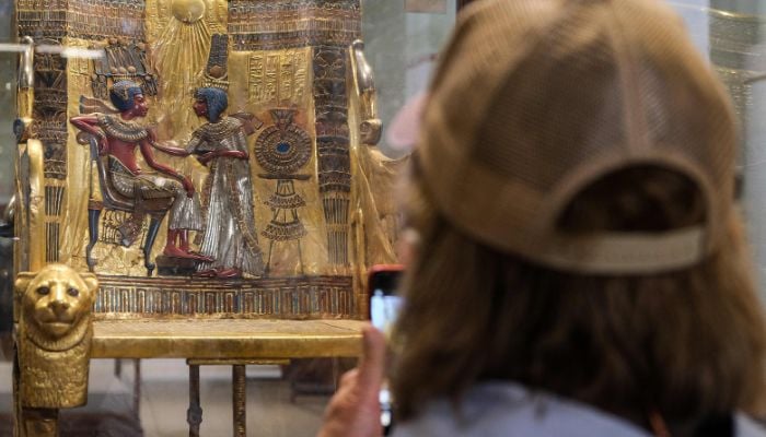 A visitor uses her phone to photograph the Golden Throne of Tutankhamun (1334-1325 BC), found in 1922 at his tomb KV62 and on display at the Egyptian Museum in the capital Cairo, on February 2, 2022. Ahead of the bicentenary of the deciphering of the Rosetta Stone -- which unlocked the key to reading ancient hieroglyphs -- and the 100th anniversary of Carter´s earth-shattering discovery, Egyptians are demanding that their contributions to the discoveries be recognised and artefacts abroad returned.