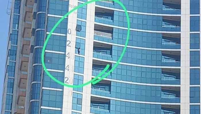 Screengrab shows a child hanging from the 13th-floor window in the Al Taawun area of Sharjah. — Gulf Today