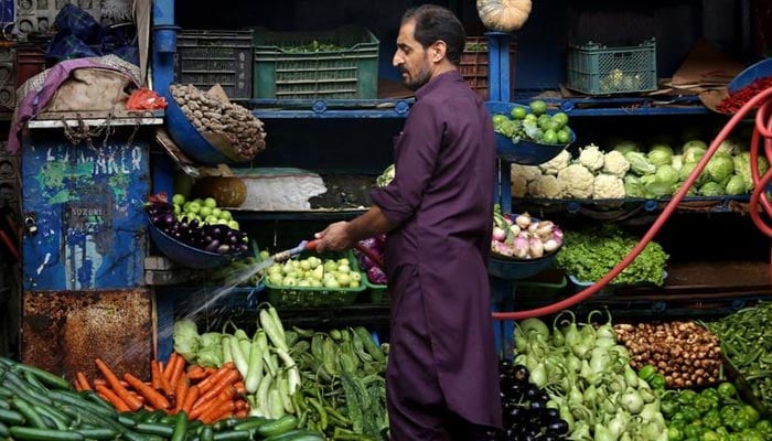 A vegetable seller waters fresh vegetables. — Reuters/File