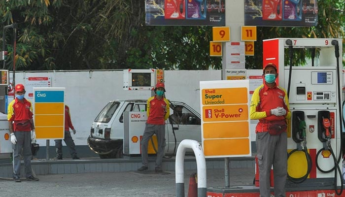 Petrol station workers wearing facemasks wait for customers next to petrol pumps in Islamabad, Pakistan, on April 22, 2020. — AFP/File