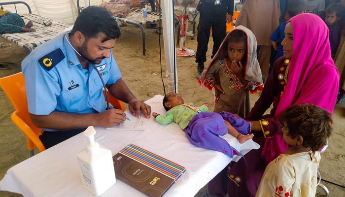 Seorang wanita, yang menjadi korban banjir, menerima bantuan medis untuk bayinya saat dia berlindung di sebuah kamp bantuan, menyusul hujan dan banjir selama musim hujan di Sehwan, Pakistan, 9 September 2022. — Reuters