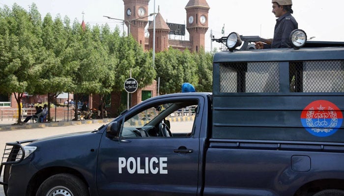 Representational image of a cop standing alert in Punjab Police van in Lahore. — Online/File