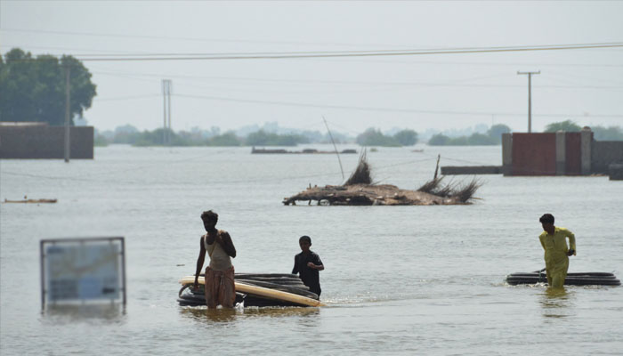 Flood-affected people shift materials across a flooded area at Dera Allah Yar town in Jaffarabad district, Balochistan province, on September 6, 2022. —AFP/ Fida HUSSAIN