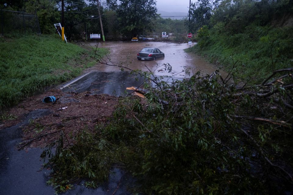 18 ستمبر 2022 کو یوکو، پورٹو ریکو میں سمندری طوفان فیونا کے علاقے کو متاثر کرنے کے بعد ایک کار سیلابی پانی میں بیٹھی ہے