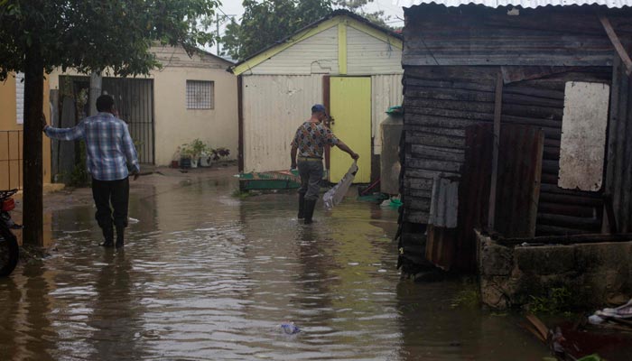 Men wade through a flooded street in Nagua, Dominican Republic, on September 19, 2022, after the passage of Hurricane Fiona. — AFP