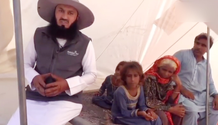 Zimbabwean Islamic scholar Ismail ibn Musa Menk (left) sits flood affectees in Pakistans Sindh province in this undated photo. — Instagram/Mufti Menk