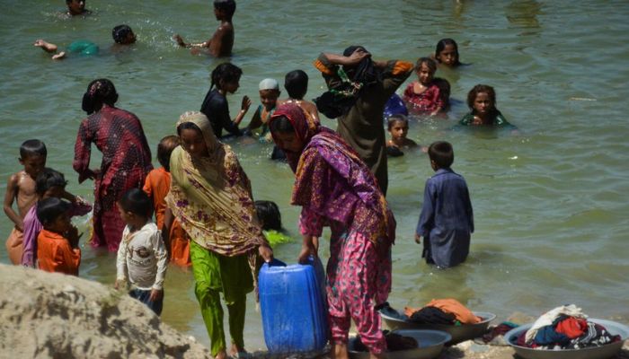 People, displaced because of the floods, carry a canister filled with flood water while taking refuge in a camp, following rains and floods during the monsoon season in Sehwan, Pakistan September 20, 2022. — Reuters