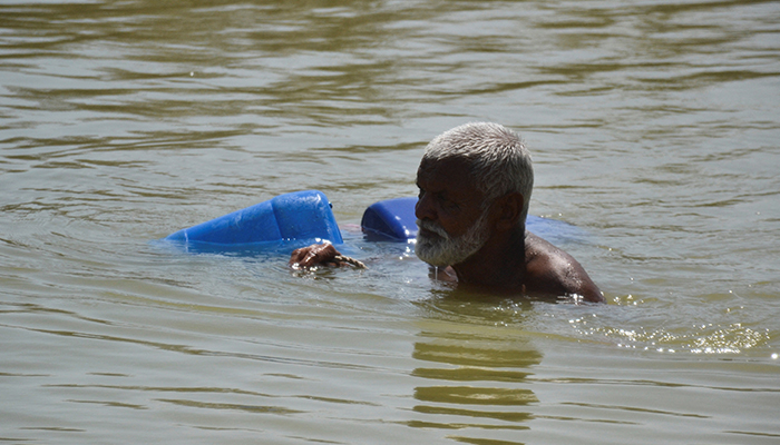 A man, displaced because of the floods, wades through flood water to fill the canisters, following rains and floods during the monsoon season in Sehwan, Pakistan September 20, 2022. — Reuters