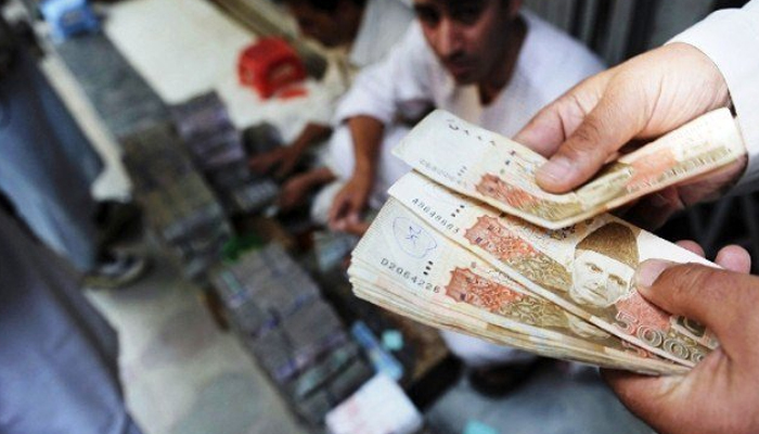 A currency dealer counts Rs5,000 notes at a shop in Karachi, Pakistan In this undated photo. — AFP/File