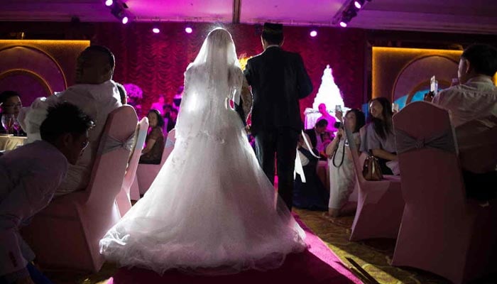 This file photo shows a newly married couple entering a wedding hall during their wedding reception at the Al Meroz hotel in Bangkok. — AFP