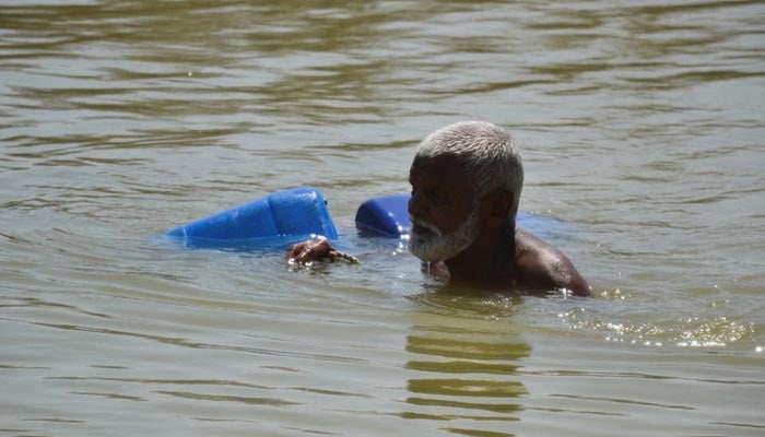 A man, displaced because of the floods, wades through flood water to fill the canisters, following rains and floods during the monsoon season in Sehwan, Pakistan September 20, 2022. — Reuters/File