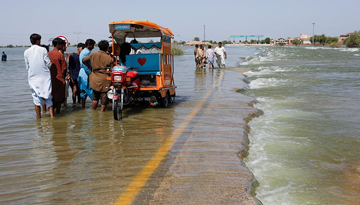 Displaced people stand on flooded highway, following rains and floods during the monsoon season in Sehwan, Pakistan, September 16, 2022. — Reuters