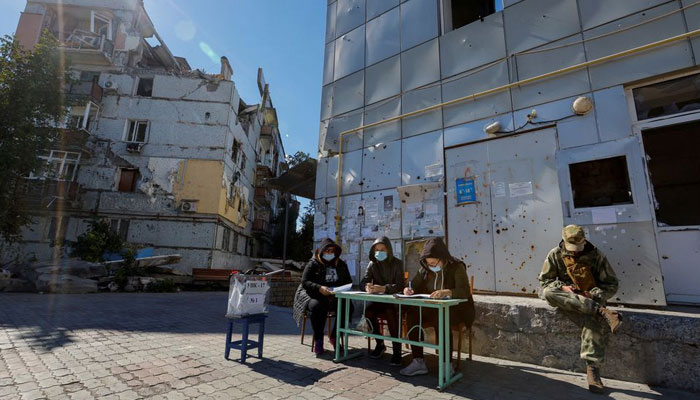 Members of an electoral commission wait for voters near a destroyed residential building on the third day of a referendum on the joining of the self-proclaimed Donetsk Peoples Republic (DPR) to Russia, in Mariupol, Ukraine September 25, 2022. — Reuters