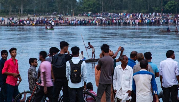 People gather along the banks of the Karatoya river after the boat capsized near the town of Boda in Bangladesh. — AFP