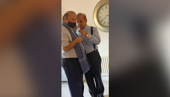 Prime Minister Shehbaz Sharif whispering in his brother PML-N supermo Nawaz Sharifs ears at Jawad Sohrab Maliks apartment. — Reporter