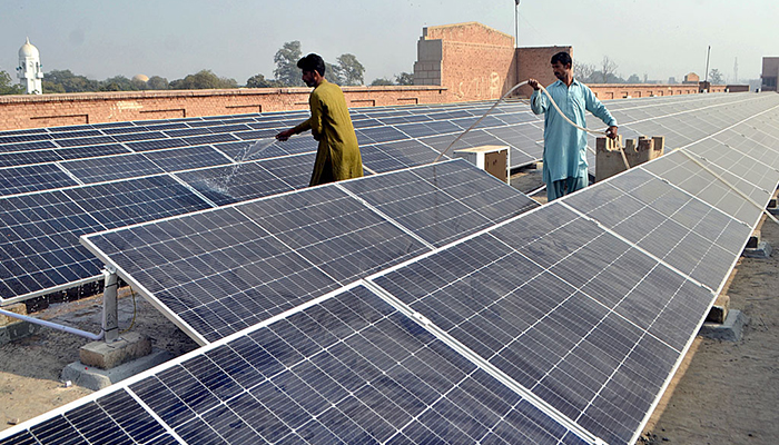 Workers washing 300 KWP solar PV system after its installation at Nishtar Medical University and Hospital in Multan, on December 4, 2022. — APP