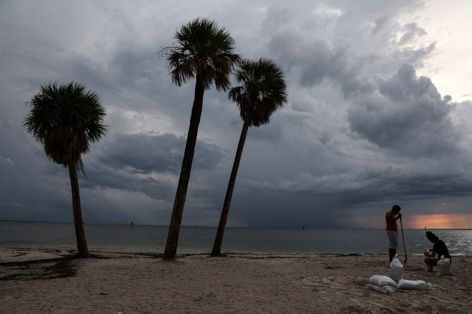 26 ستمبر 2022 کو امریکی ریاست فلوریڈا کے ٹمپا میں بین ٹی ڈیوس بیچ پر سمندری طوفان ایان تیز ہواؤں، طوفانی بارشوں اور ایک طاقتور طوفان کے ساتھ ریاست کی طرف بڑھتے ہوئے مقامی باشندے ریت کے تھیلے بھر رہے ہیں۔ — رائٹرز