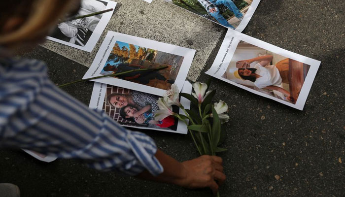28 ستمبر 2022 کو میڈرڈ، اسپین میں مہسا امینی کی موت کے بعد ایران میں حکومت مخالف مظاہروں کی حمایت میں ایک شخص ایرانی سفارت خانے کے سامنے احتجاج کے دوران پھول چڑھا رہا ہے۔ - رائٹرز