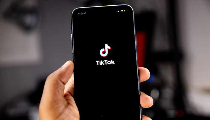 A person holds a phone with the TikTok app showing on the screen. — Unsplash