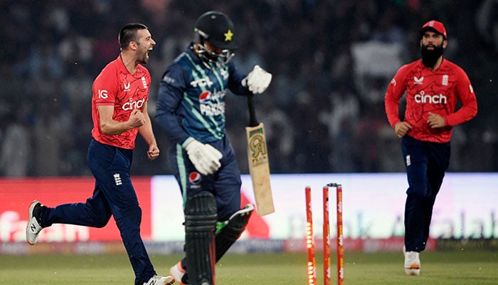 England´s Mark Wood celebrate after the dismissal of Pakistan´s Asif Ali (R) during the fifth Twenty20 international cricket match between Pakistan and England at the Gaddafi Cricket Stadium in Lahore on September 28, 2022. — AFP