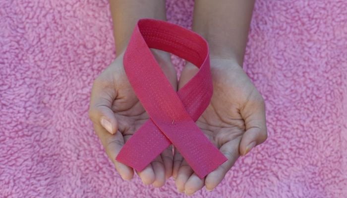 Woman holds a pink ribbon.— Unsplash