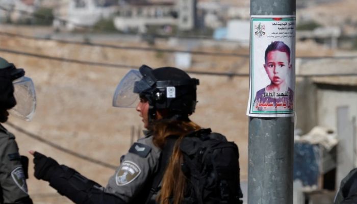 Israeli forces stand next to a picture of seven-year-old Palestinian boy Rayan Suleiman, who according to his father has died of heart failure after being chased by Israeli soldiers.— Reuters