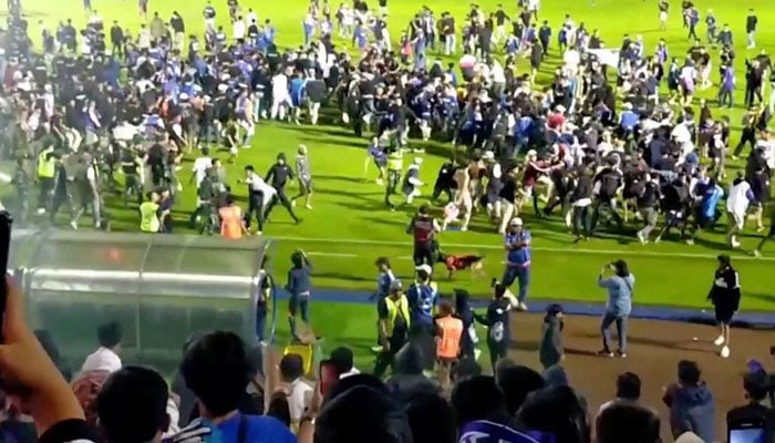 Fans invade the soccer field after a match between Arema FC and Persebaya Surabaya at Kanjuruhan Stadium, Malang, Indonesia Oct 2, 2022 in this screen grab taken from a REUTERS video