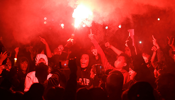 Football fans light a red flare during a vigil at Gelora Bung Karno Stadium area, following a riot after the football match between Arema vs Persebaya in Jakarta, Indonesia, October 2, 2022. — Reuters