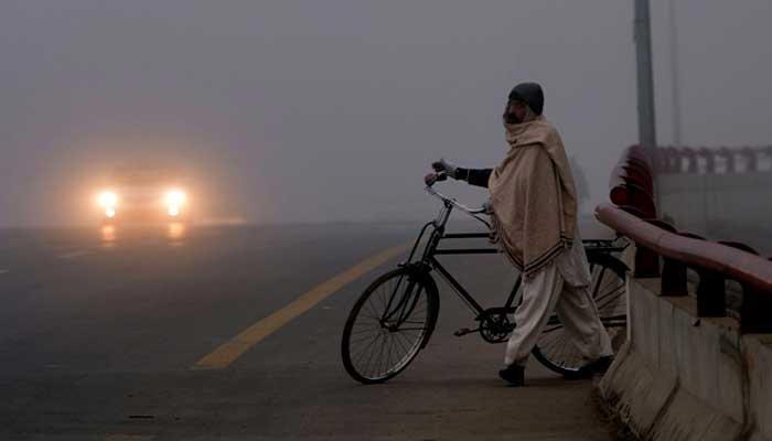A man draped in a shawl makes his way across a bridge in Karachi. — AFP/File