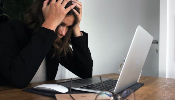 A woman sits stressed in front of her laptop. — Unsplash