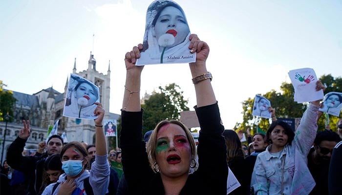 People chant slogans and hold the pictures of Mahsa Amini during a demonstration in central London on October 8, 2022. — AFP